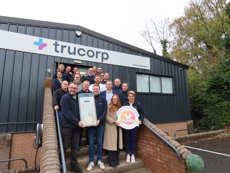 Members of staff of Trucorp in front of company's logo.