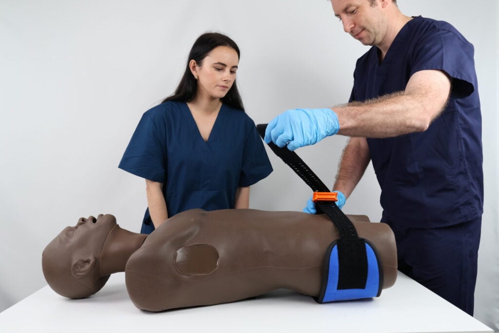 Instructor teaching student how to apply pelvic binder using TruMan Trauma Adult